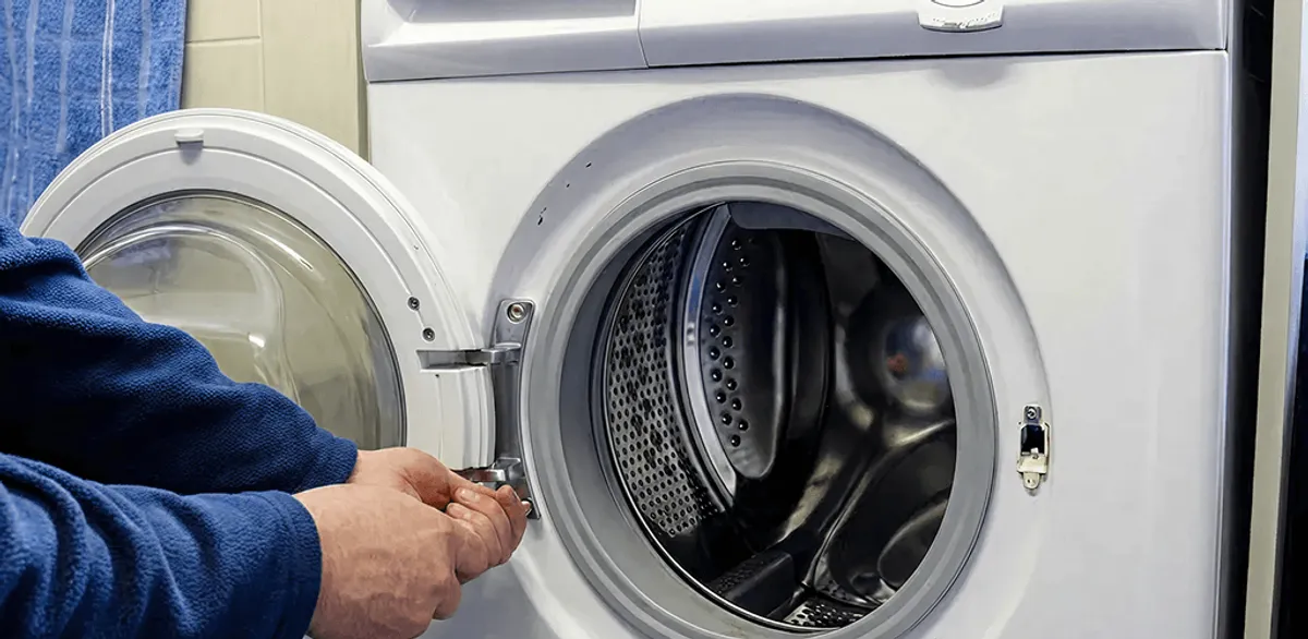 Washing machine repair handyman checking a front-load washer door and latch in Anchorage, AK